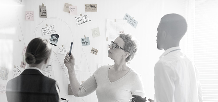 Analysts standing around a whiteboard with notes affixed