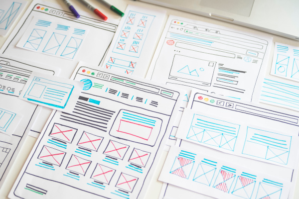 Many overlapping web application wireframe designs on a drafting table.